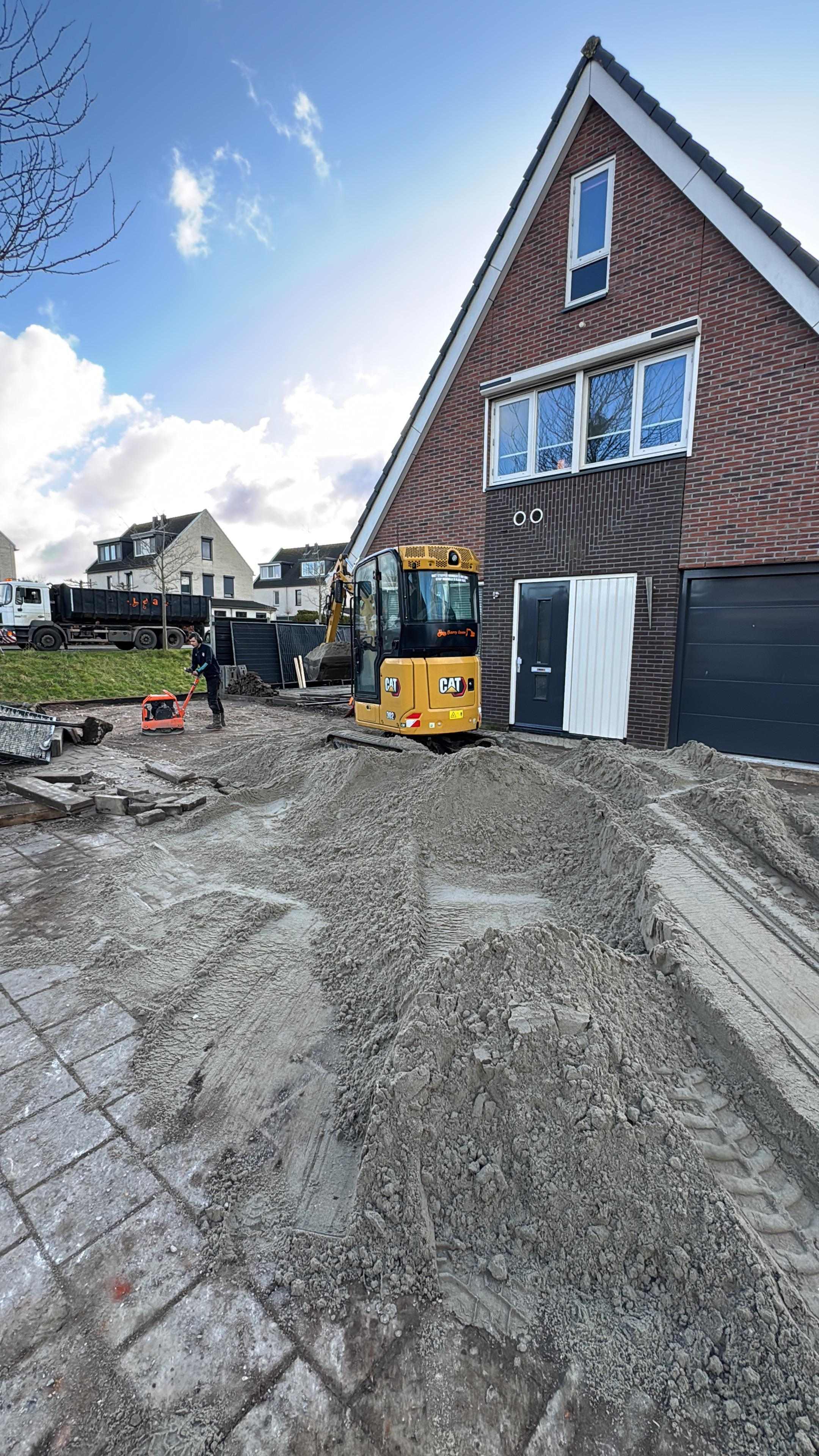 CAT graafmachine bij grondwerk voor nieuwe oprit bij woning