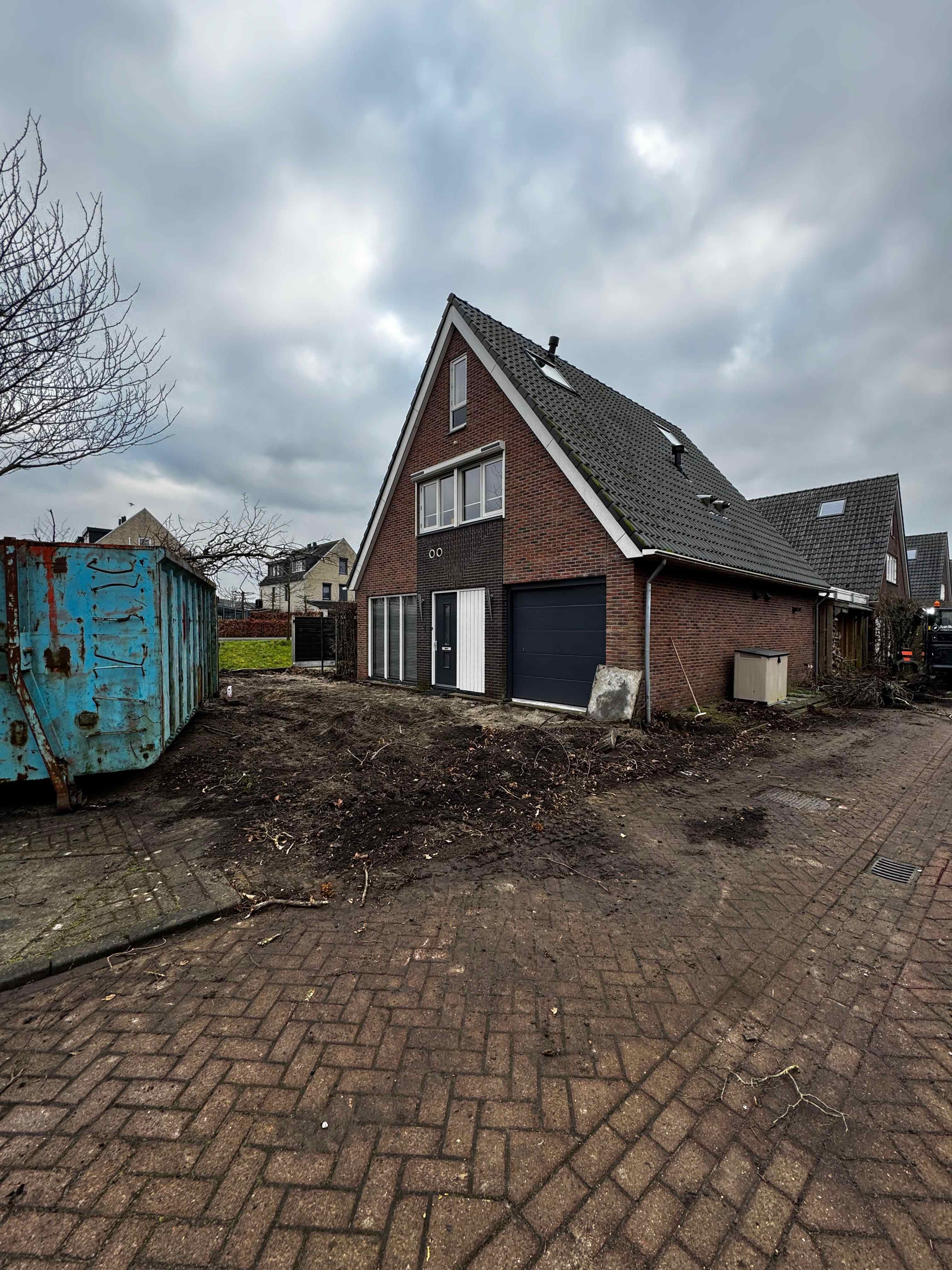 Woning met puincontainer en grondwerk tijdens bouwfase