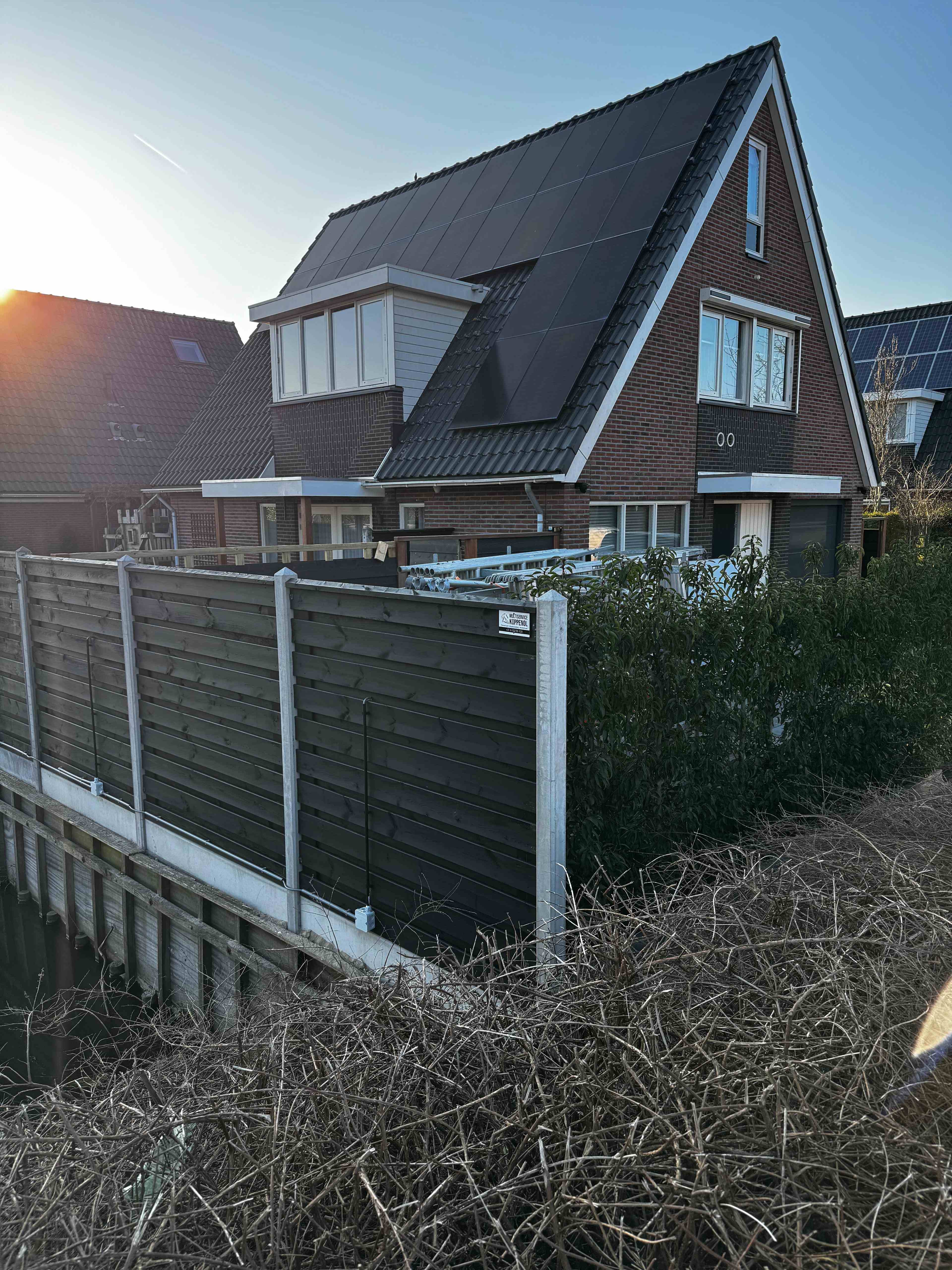 Woning met zonnepanelen, dakkapel en houten schutting aan het water