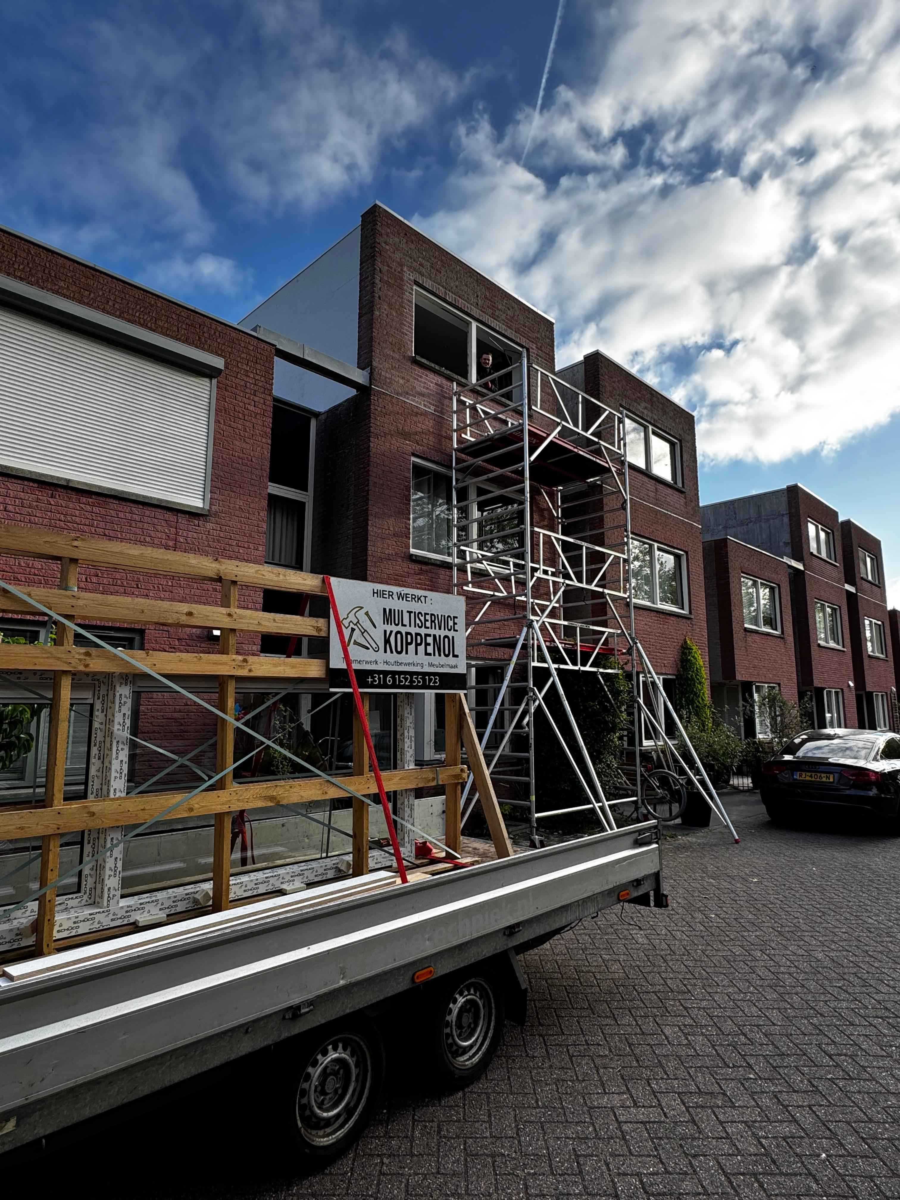 Steiger met Multiservice Koppenol bord bij kozijnplaatsing aan modern pand