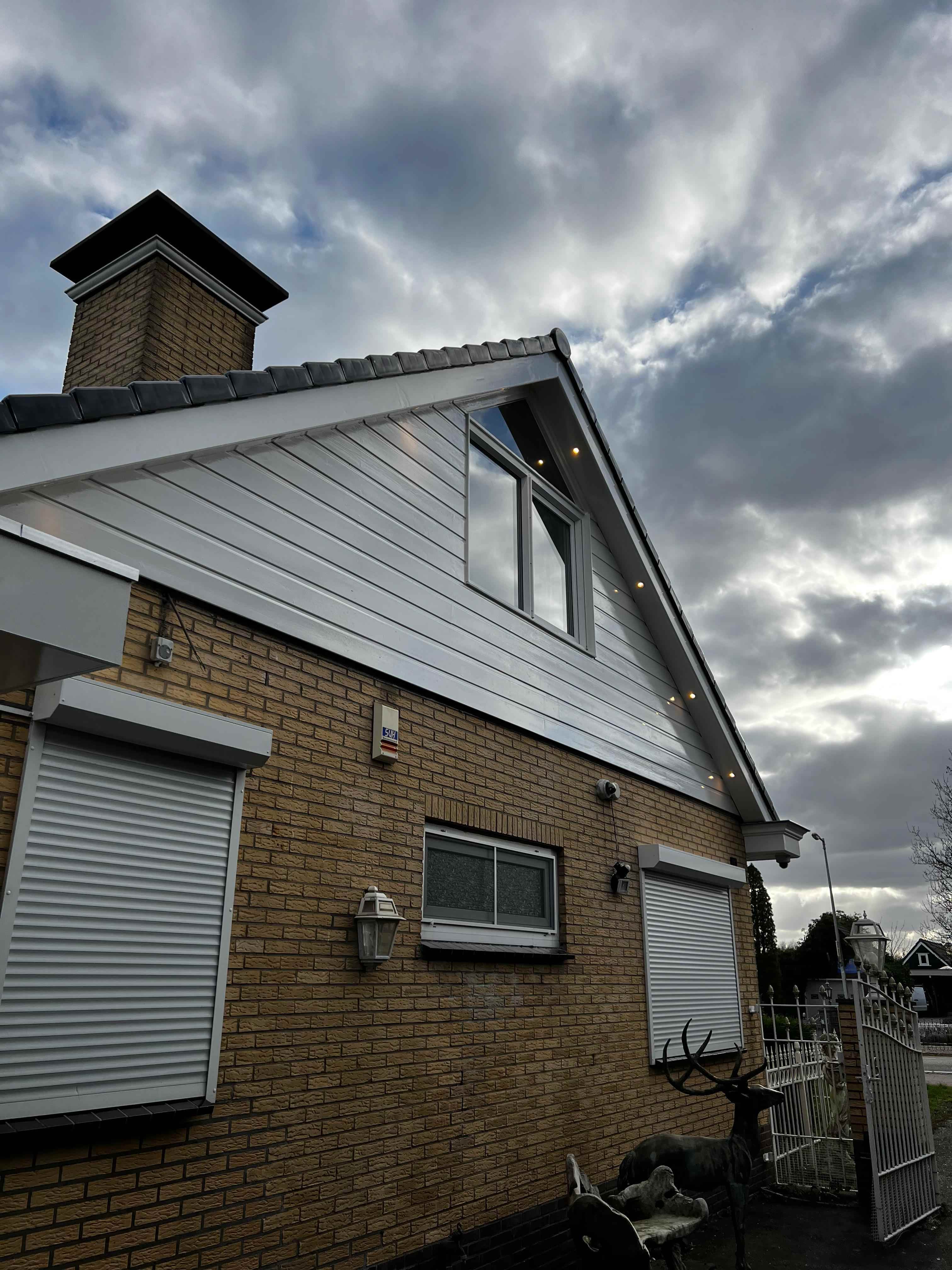 Witte gevelbekleding met inbouwspots op topgevel van woning