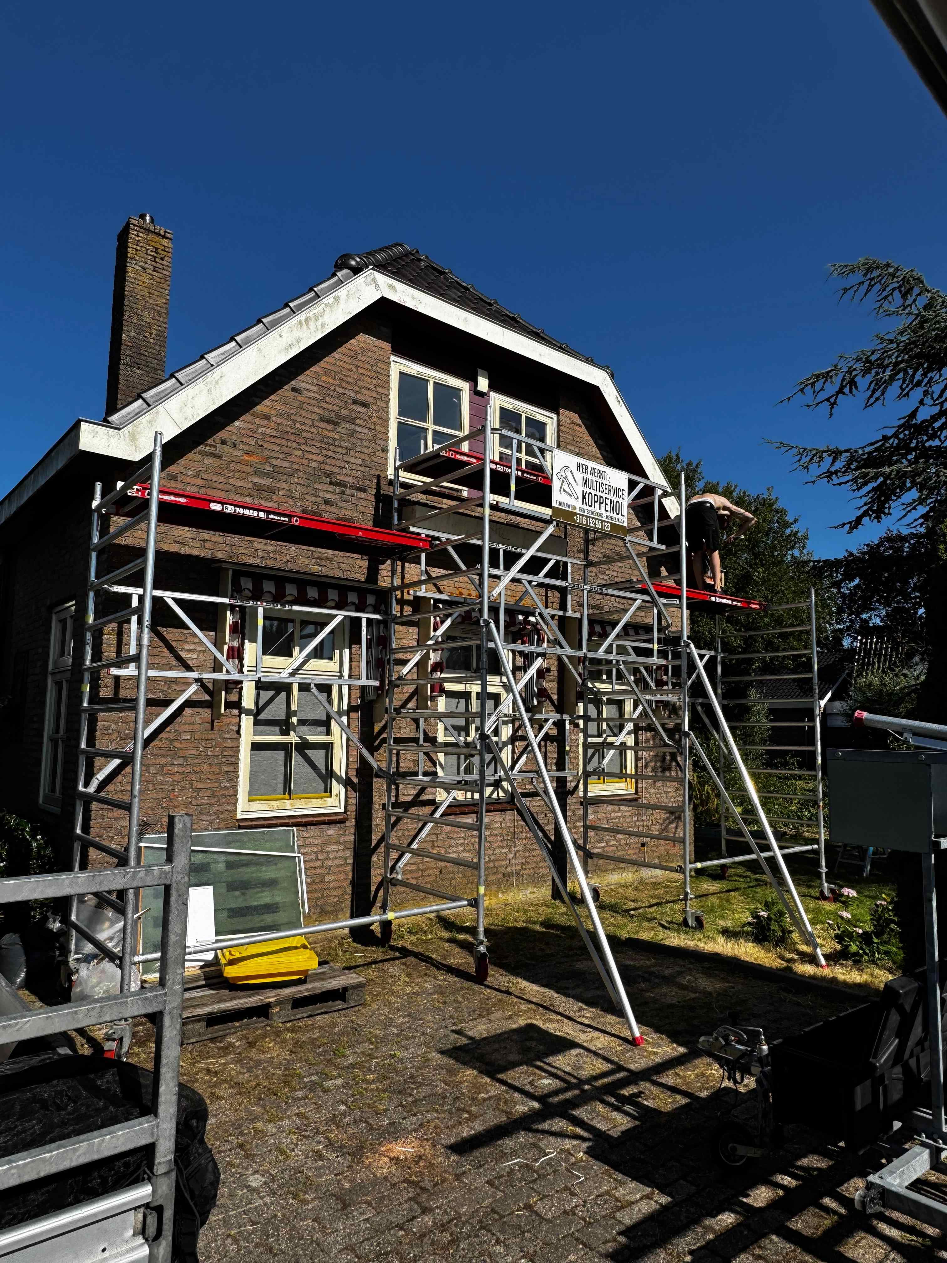 Steiger met Multiservice Koppenol banner voor schilderwerk aan voorgevel