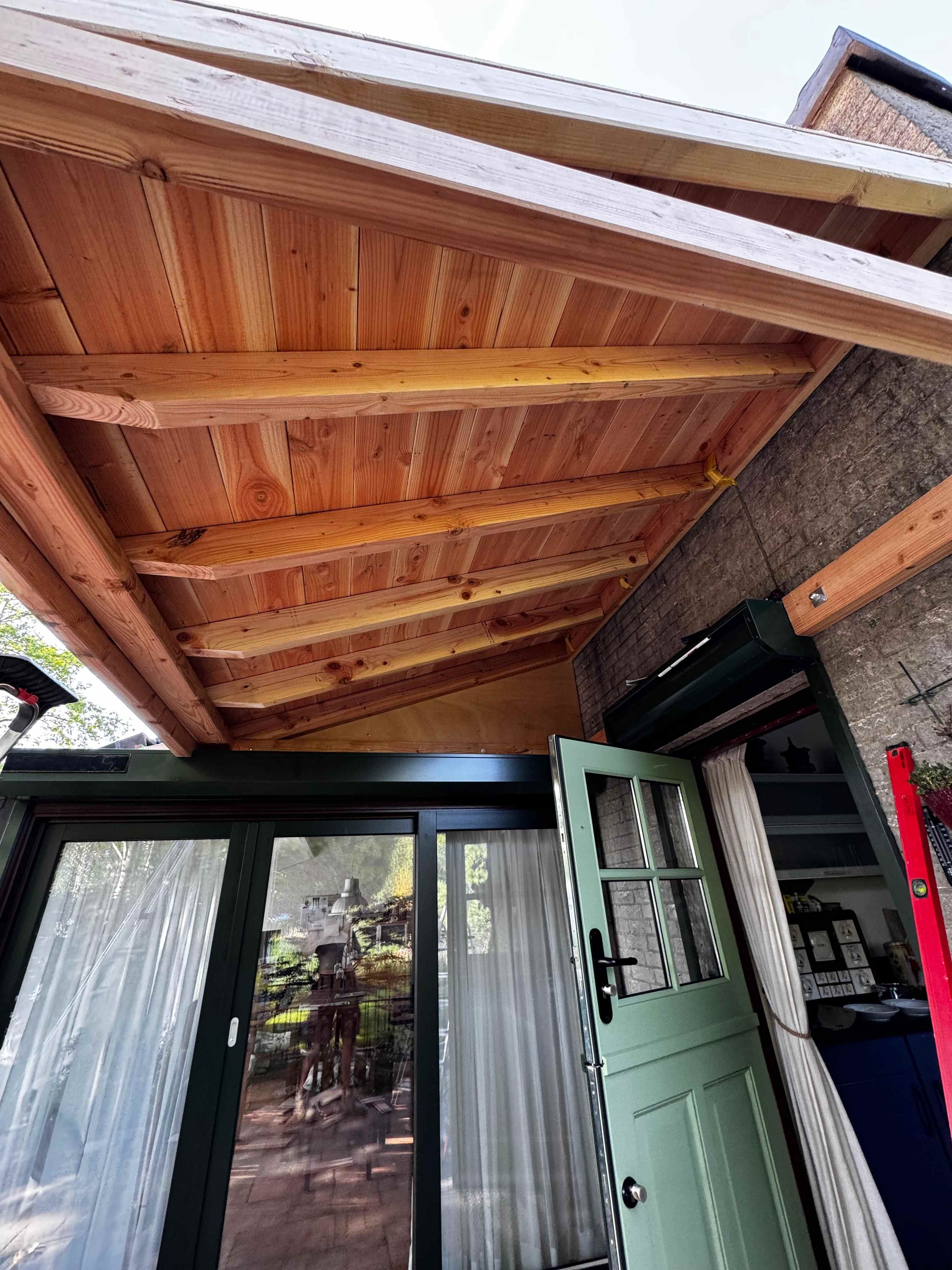 Detail douglas houten plafond met balken en groene deur