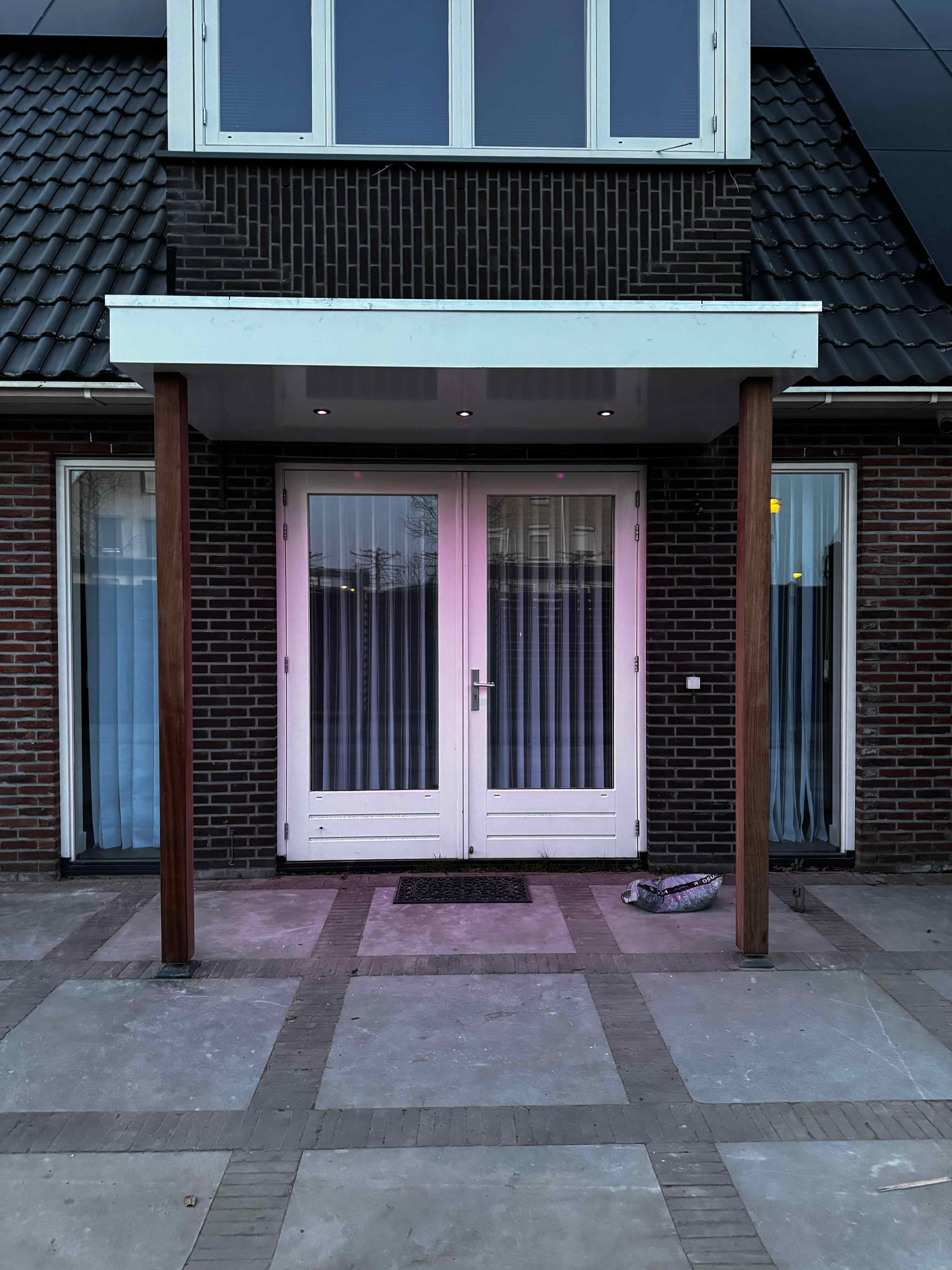 Entree overkapping met hardhouten palen en inbouwspots in schemering