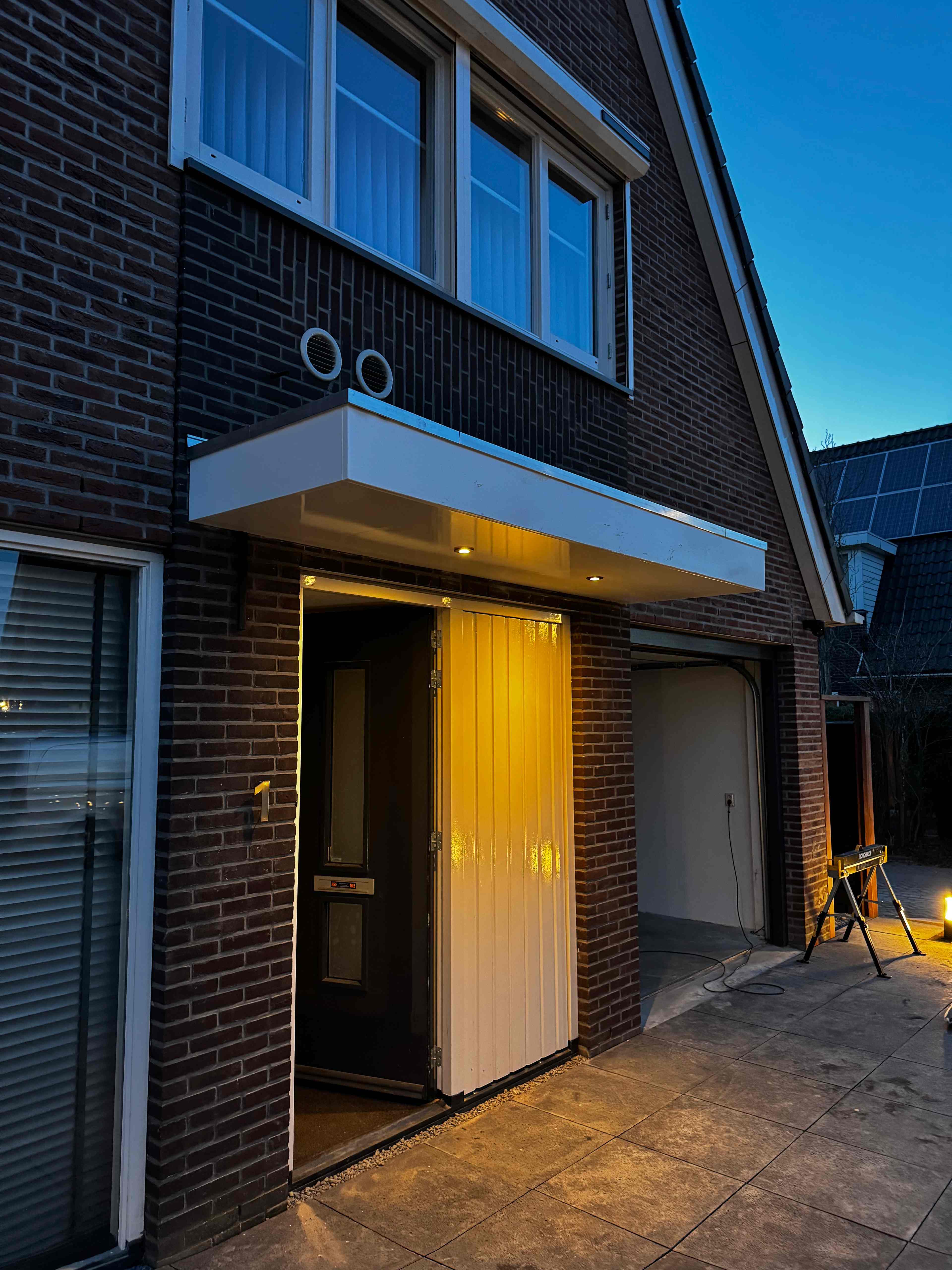 Entreeluifel met inbouwspots boven voordeur bij avond