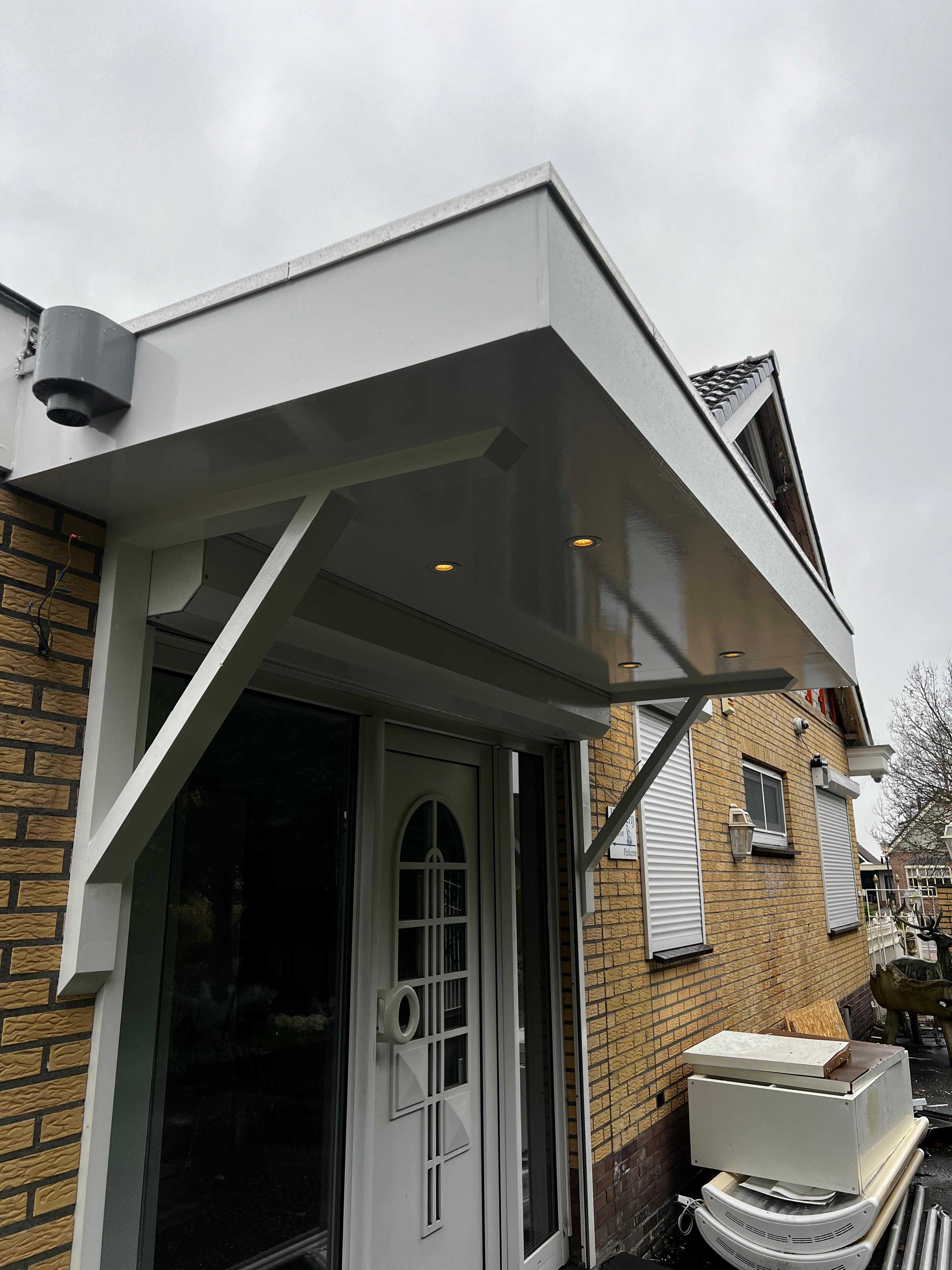 Witte entreeluifel met schoren en inbouwspots boven voordeur