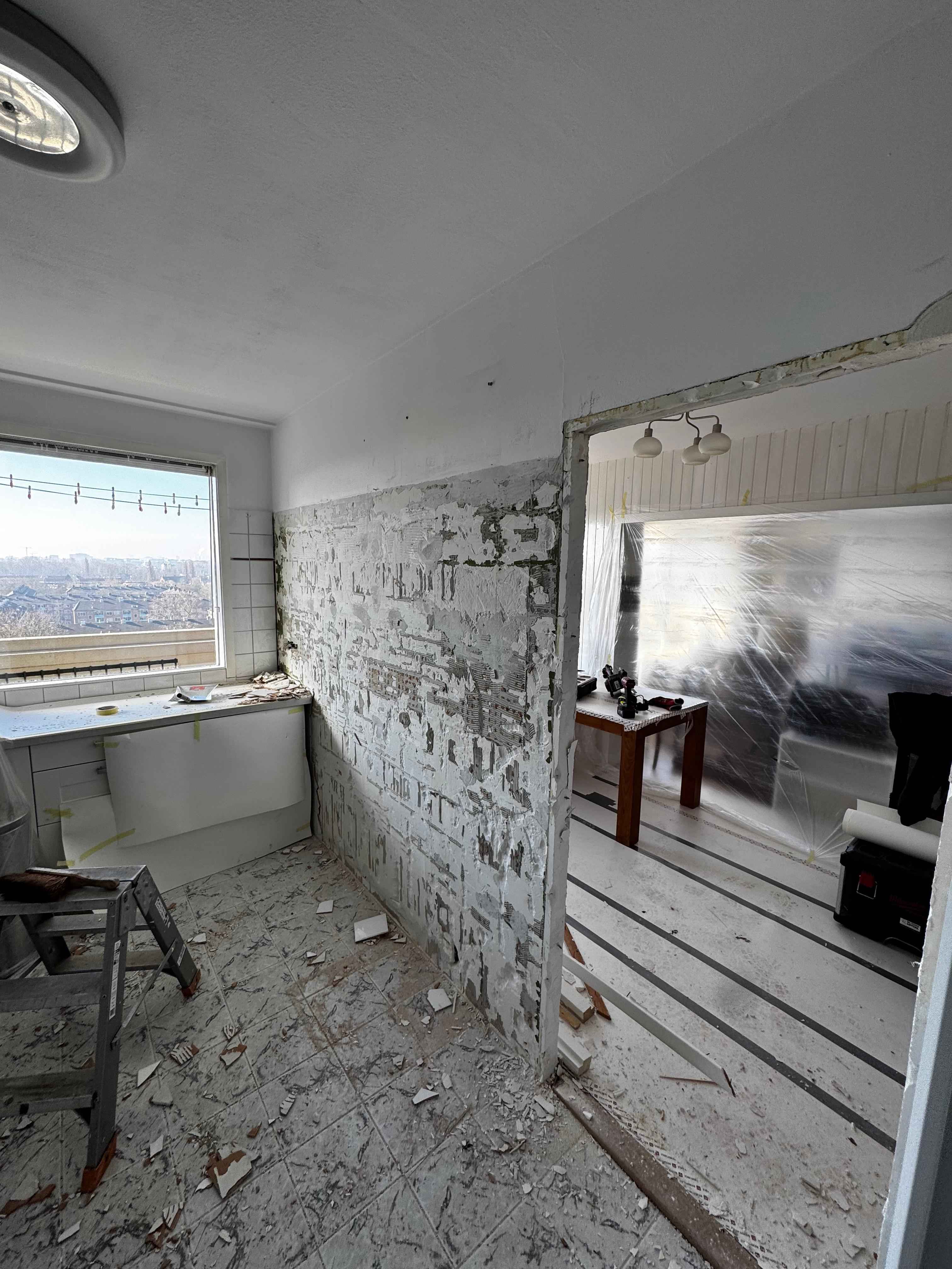 Kamer tijdens stripfase met verwijderde tegels, gereedschap en uitzicht over de wijk