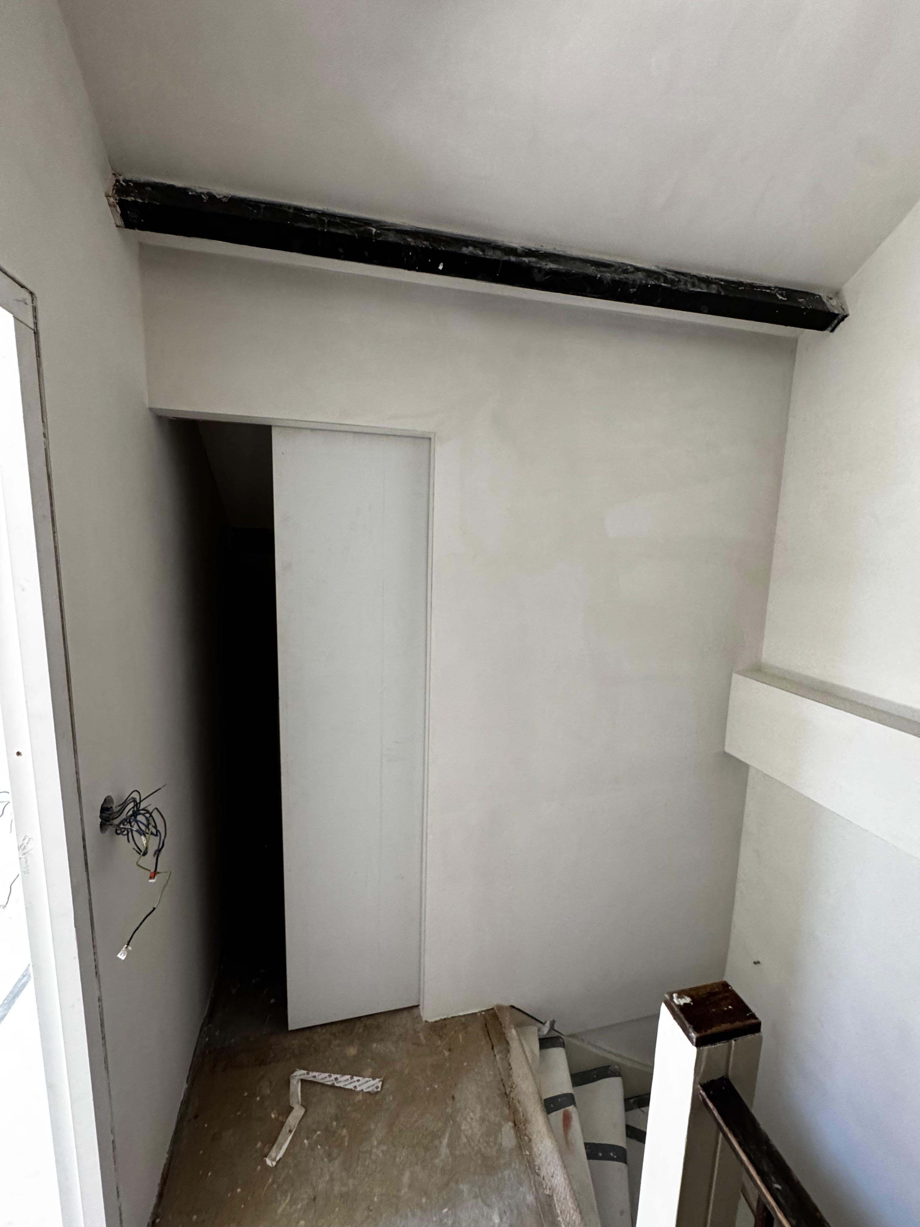 Trappenhuis met nieuw stucwerk en schuifdeur tijdens renovatie