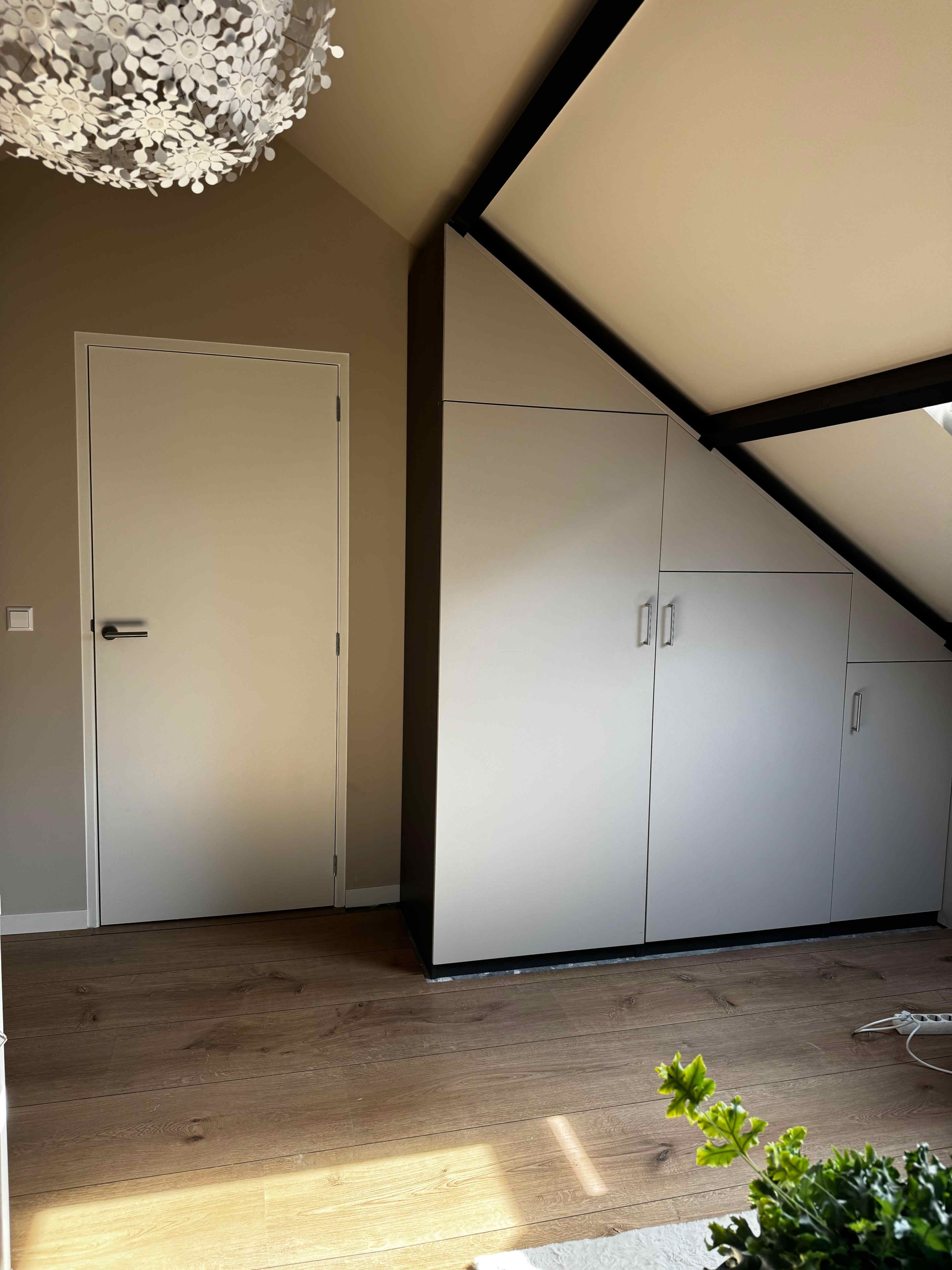 Inbouwkasten op maat onder schuin dak met donkere balken