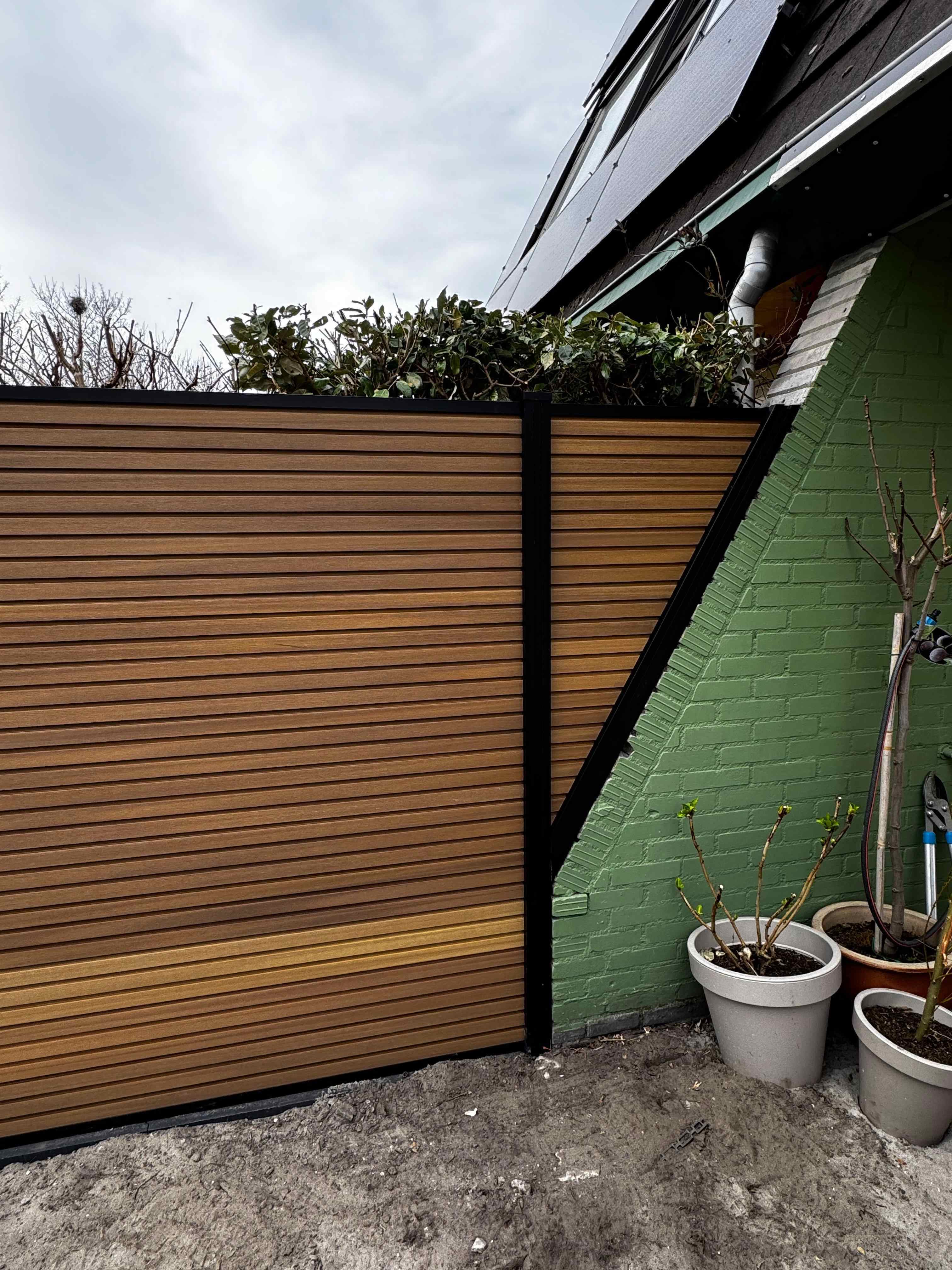 Moderne schutting met horizontale houten panelen en stalen frame