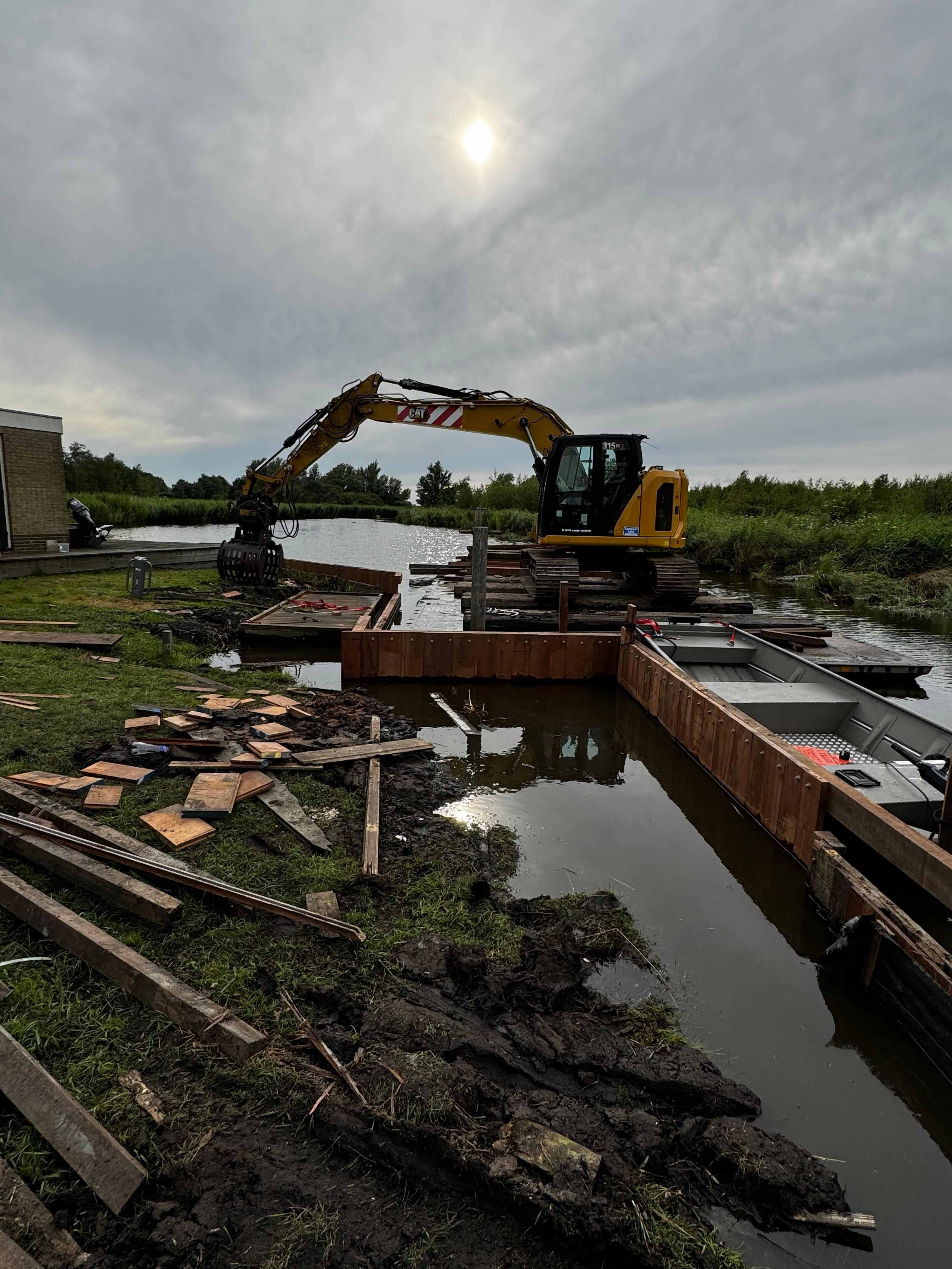 CAT graafmachine op ponton bij beschoeiingswerkzaamheden aan het water