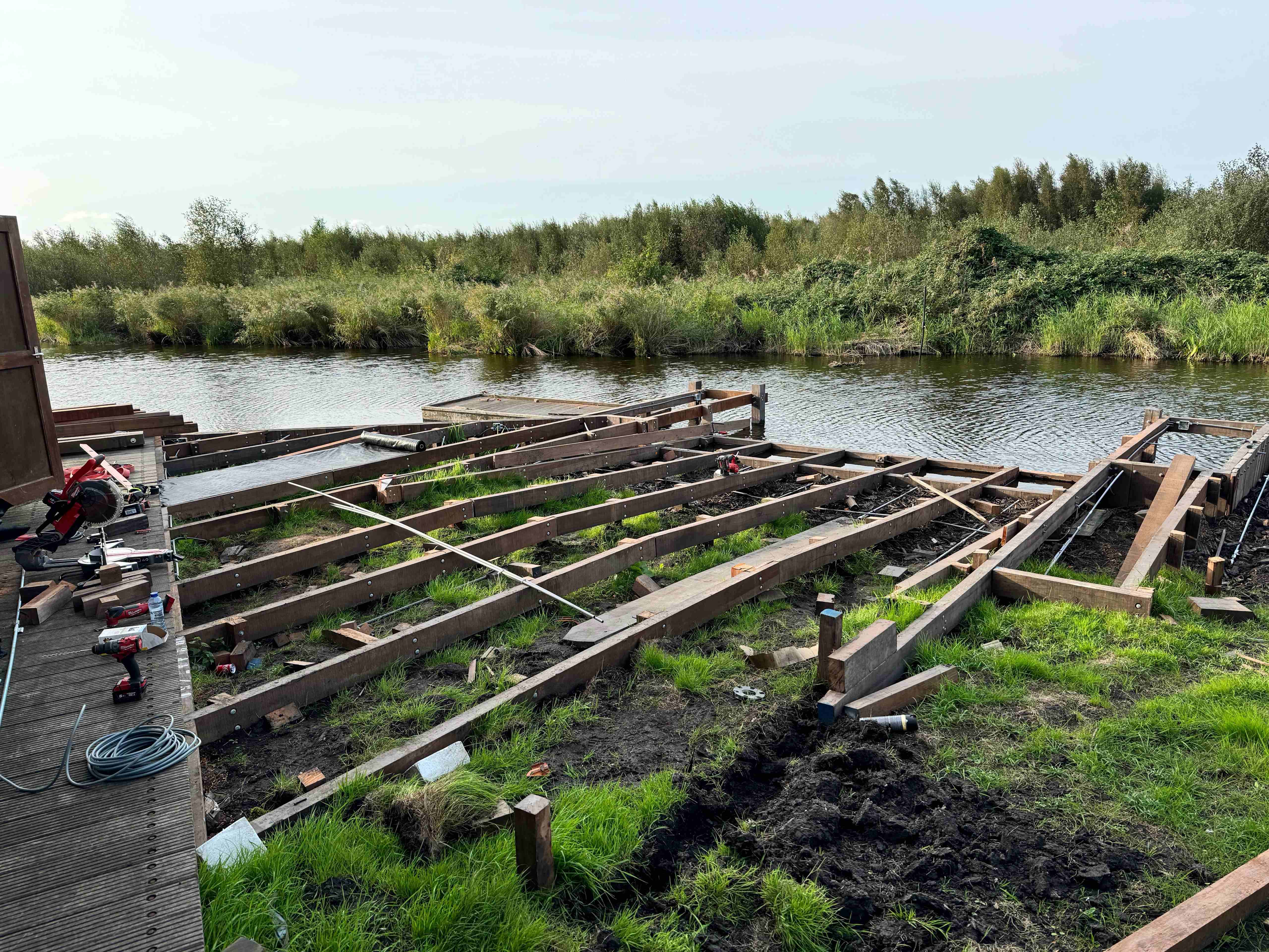 Hardhouten steiger in aanbouw met balkenconstructie aan het water