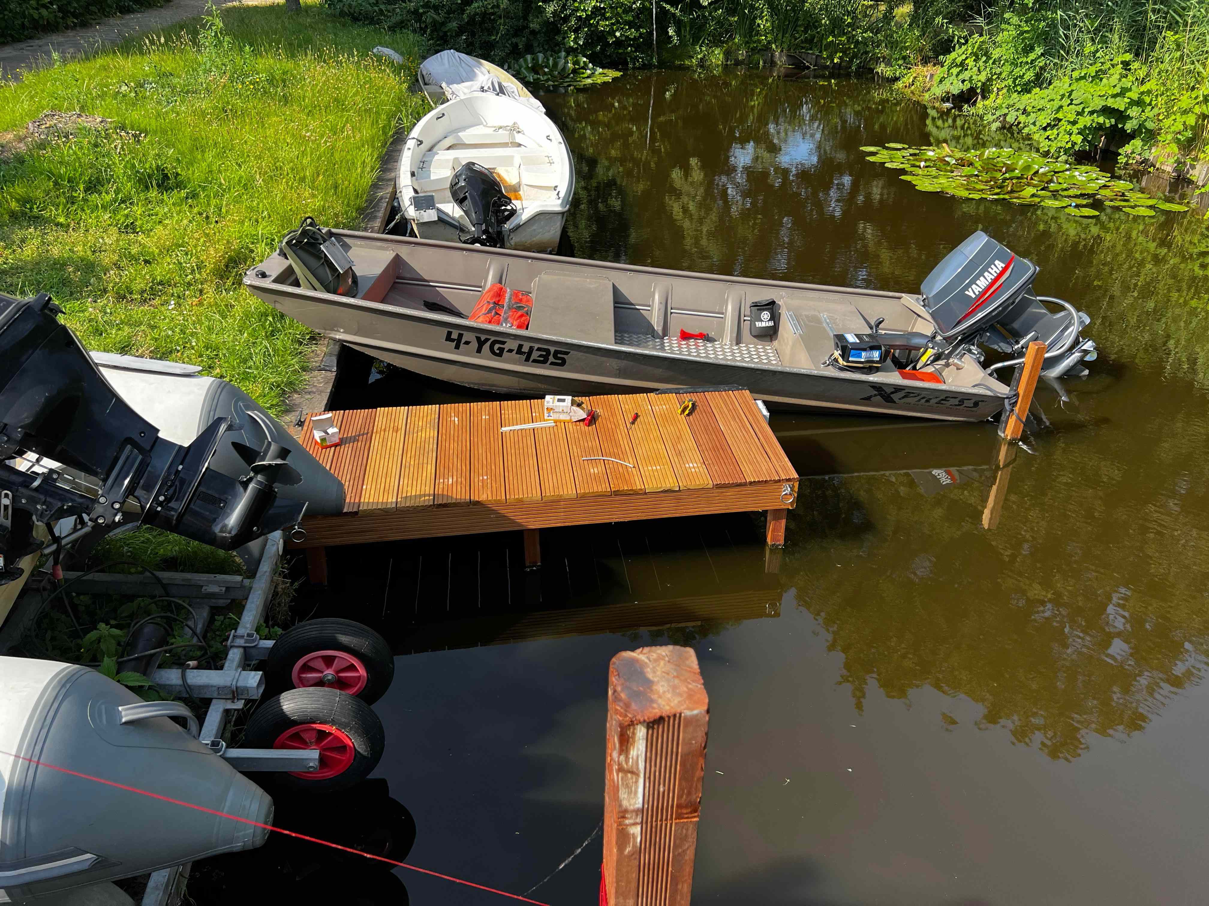 Kleine hardhouten steiger met aangemeerde boten aan sloot