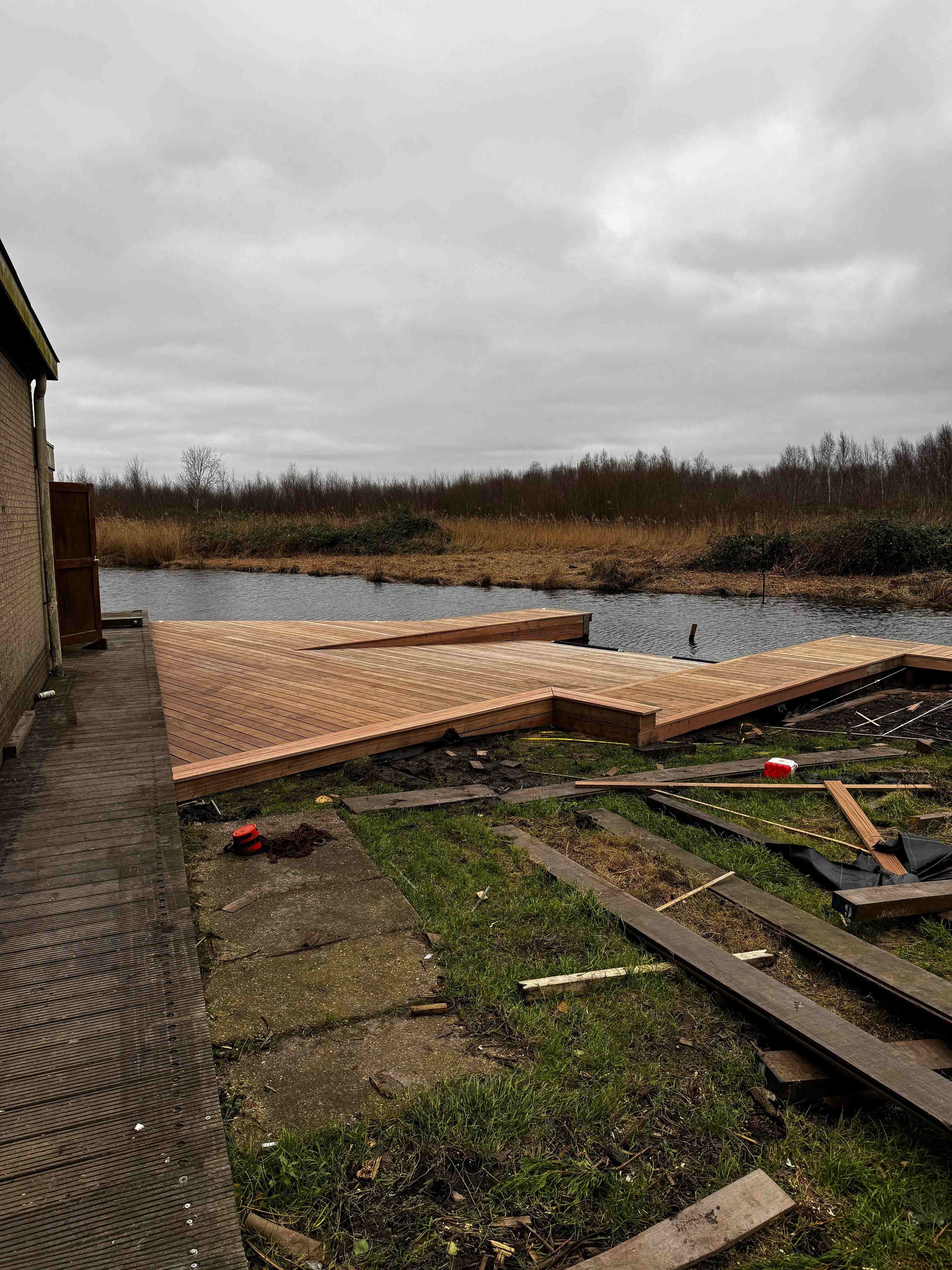 Grote hardhouten vlonder in L-vorm aan het water in polderlandschap